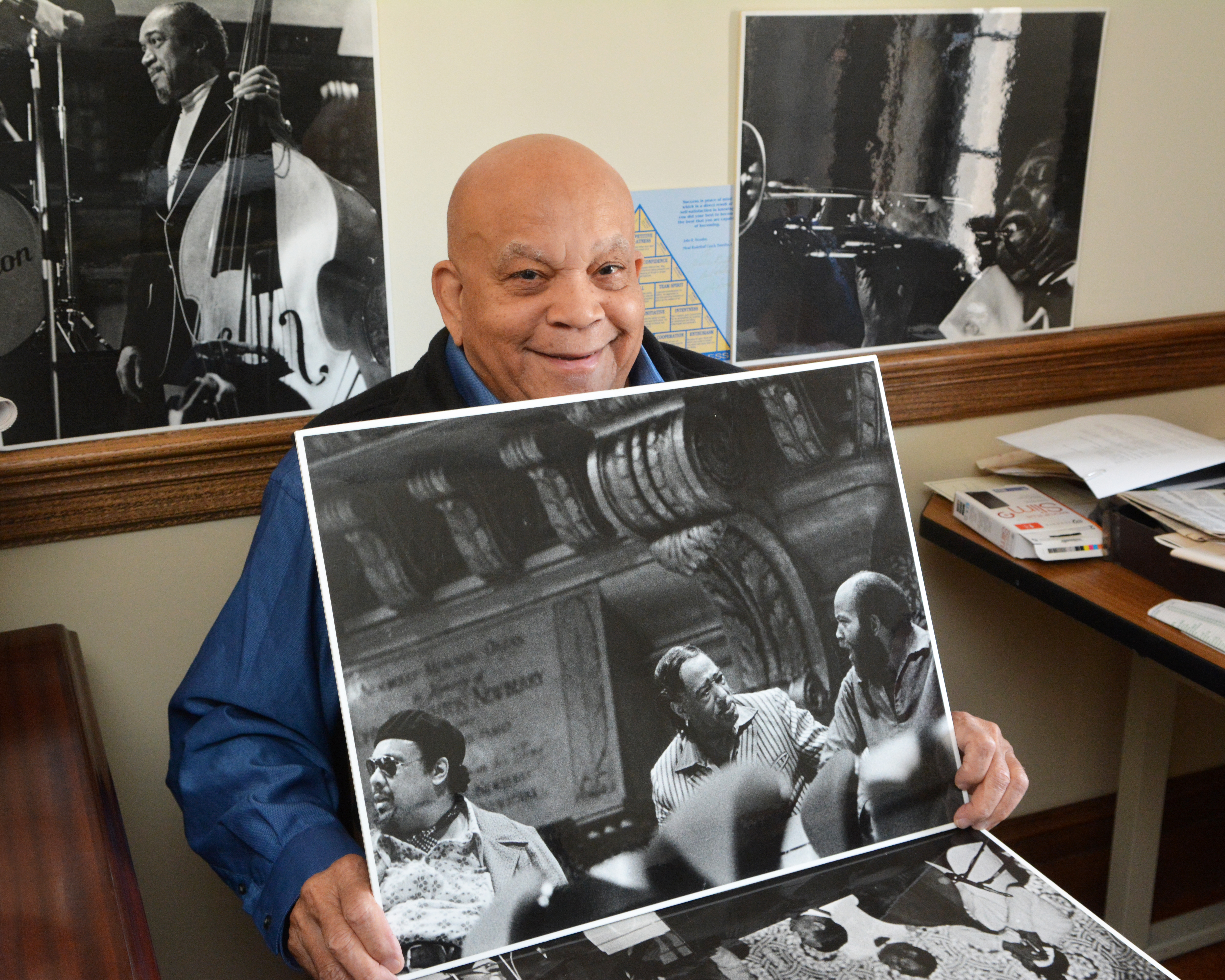 man wearing a blue shirt smiling, holding a black and white photograph