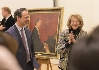 a man in a suit standing with a woman in tweed